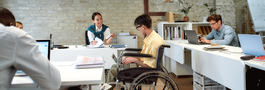 People working in an office environment; one person uses a wheelchair